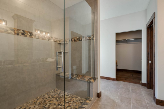 24Master shower-FULL Large bathroom walk in shower with marble seat and tiles with accents of river rock.