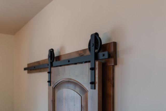 Arctic Loop by Premiere Quality Homes New modern sliding barn door with black metal hardware on a neutral wall.