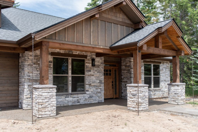 Rustic charm meets modern living: a custom-built cozy wood and stone house facade with inviting front porch.