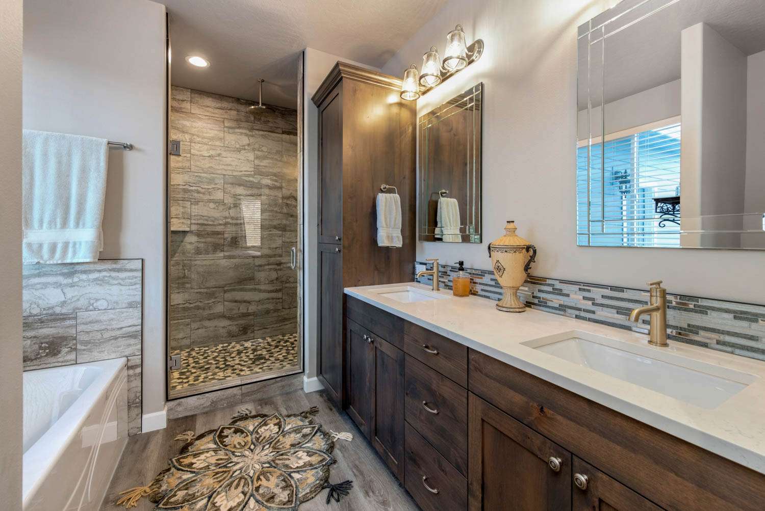 18813 W Mincoda Rd Modern bathroom with dual sinks, wooden cabinetry, a walk-in shower with new stone tile, and elegant light fixtures.
