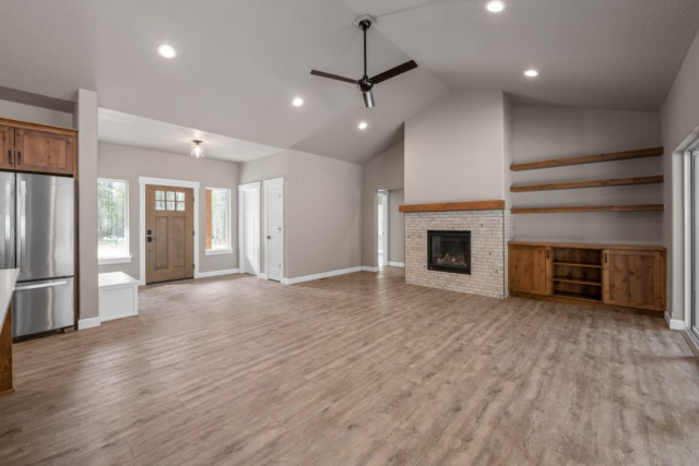 Peacock Lane by Premier Quality Homes Spacious and modern living room with wooden floors, a fireplace, and elegant designed built-in shelves, accentuated by natural light from the entrance doors.