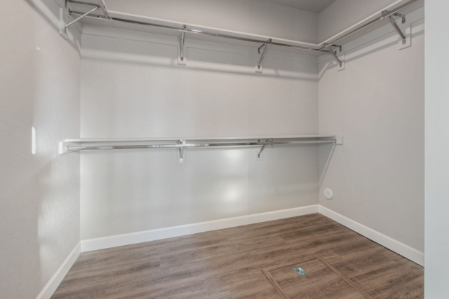 17207 W Rolling Hills Ln A custom-built, modern walk-in closet featuring installed metal rods and shelf systems on a neutral-colored wall with laminate wood flooring.