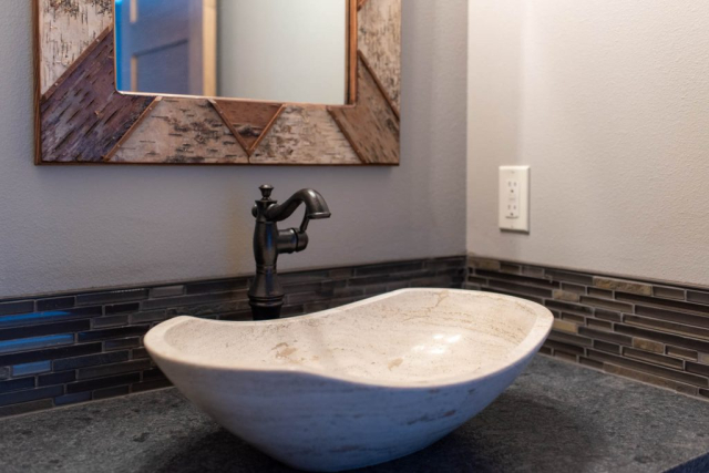 Woodlake Drive by Premiere Quality Homes Modern bathroom with a vessel sink and black faucet, complemented by a new mosaic tile backsplash and a framed mirror.