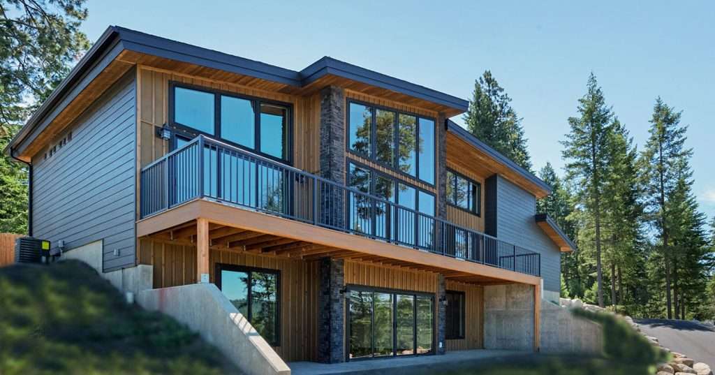Woodlake Dr-144 (1) Tall windows on a modern custom home with tall evergreen trees behind it.