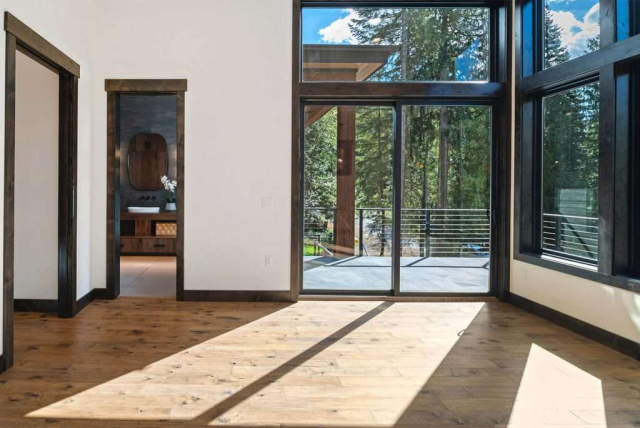 parade-house-22 A spacious room with light wood flooring and white walls. Features large sliding glass door and windows. Natural light illuminates the room, creating a bright and airy atmosphere.