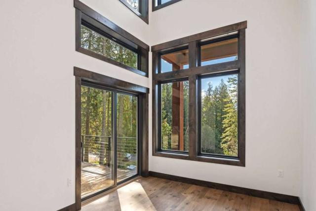 parade-house-28 A spacious room with light wood flooring and white walls. Features large sliding glass door and windows. Natural light illuminates the room, creating a bright and airy atmosphere.